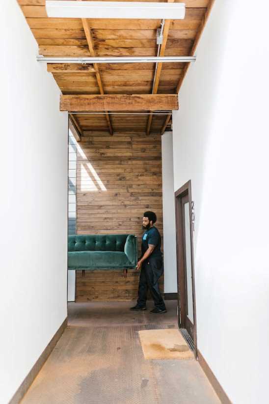 mover carrying teal sofa in a corridor, indicative of movers and packers in Goregaon East.