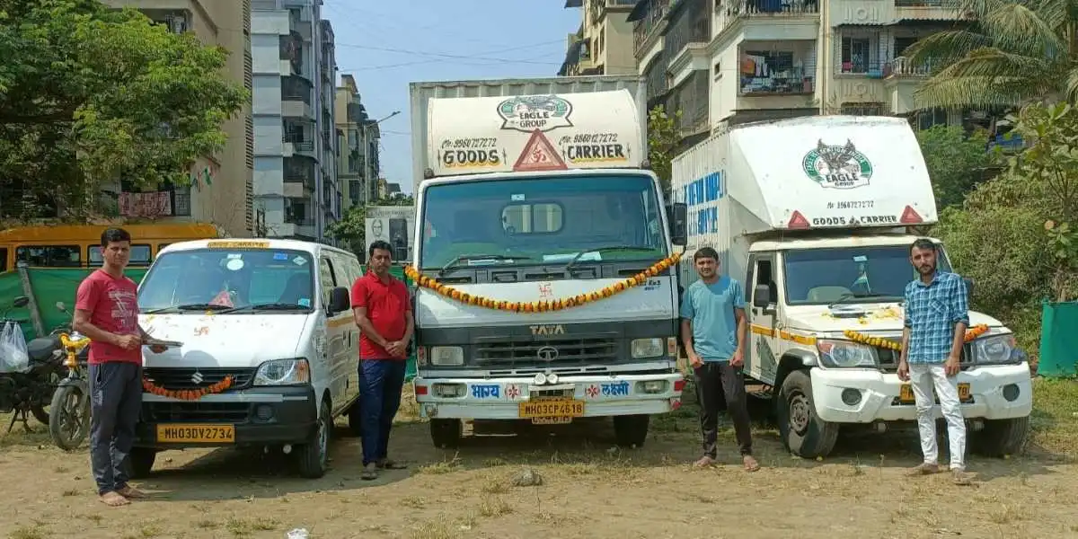 Eagle Packers and Movers in Vikhroli West team is standing in front  of 3 moving trucks